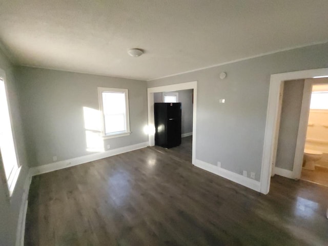 unfurnished room featuring a wealth of natural light and dark wood-type flooring