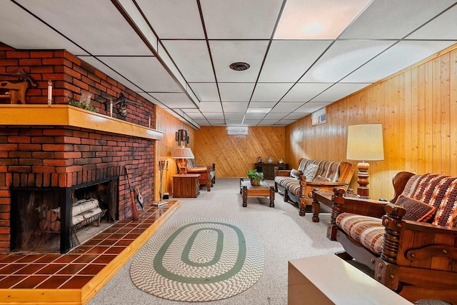 living room featuring wooden walls, a fireplace, and carpet