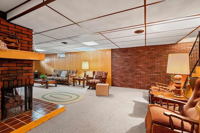 carpeted living room with a paneled ceiling and wood walls