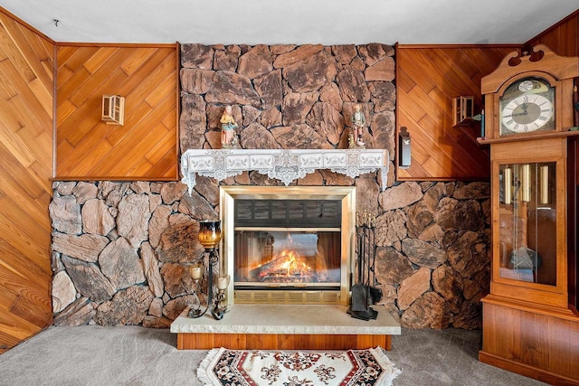 room details featuring carpet flooring, a stone fireplace, crown molding, and wood walls