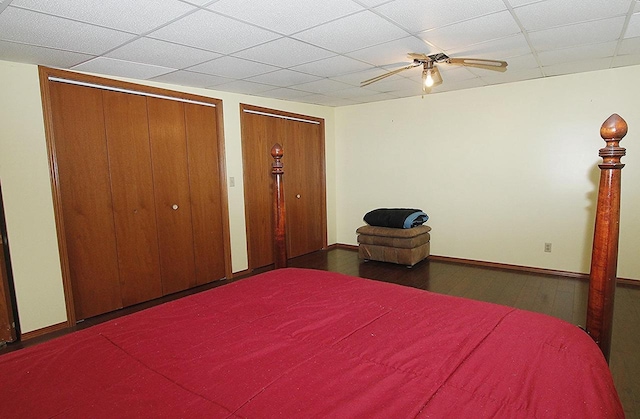 unfurnished bedroom with a paneled ceiling, two closets, and ceiling fan