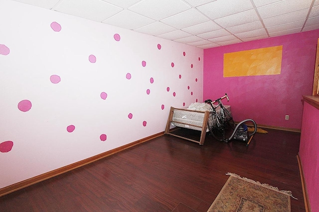 unfurnished bedroom featuring a drop ceiling and dark hardwood / wood-style floors