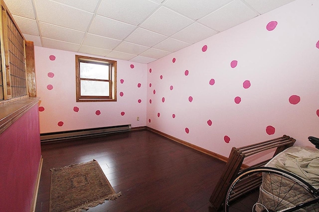 unfurnished bedroom featuring a paneled ceiling, hardwood / wood-style flooring, and a baseboard radiator