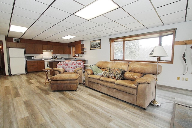 living room featuring light hardwood / wood-style flooring and a drop ceiling