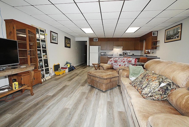 living room with a drop ceiling and light wood-type flooring