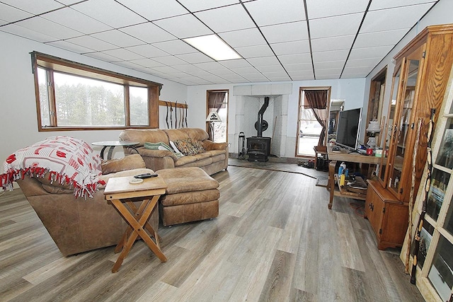 living room with a paneled ceiling, a wood stove, and light hardwood / wood-style flooring