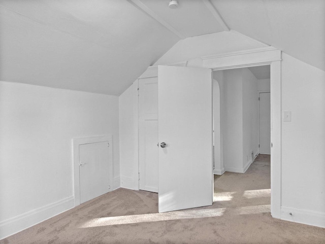 bonus room with light colored carpet and vaulted ceiling