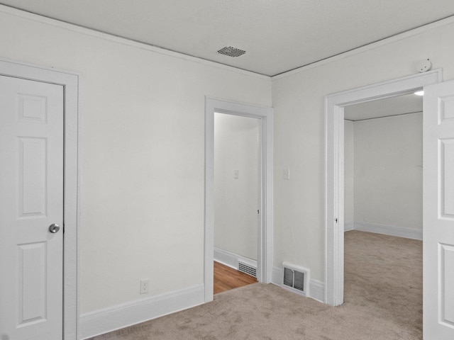 spare room featuring light colored carpet and ornamental molding