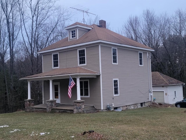 view of front of home with a porch, a garage, an outbuilding, and a front lawn