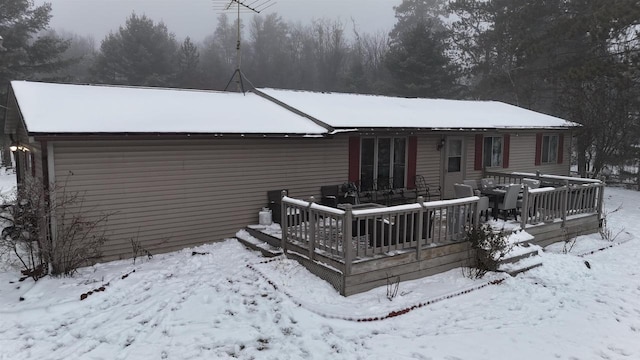 snow covered rear of property with a deck