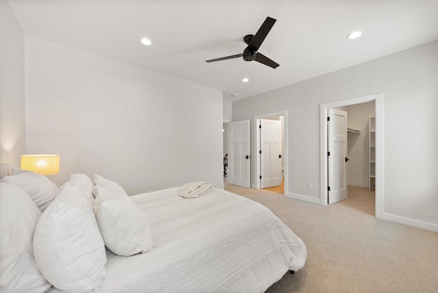 bedroom with light carpet, ensuite bath, ceiling fan, a spacious closet, and a closet