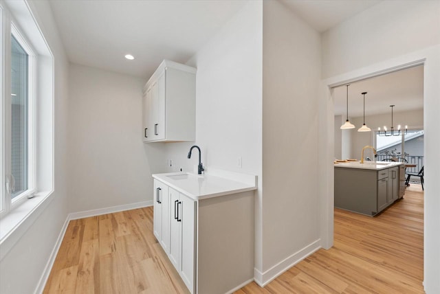 kitchen with pendant lighting, light hardwood / wood-style flooring, gray cabinets, a healthy amount of sunlight, and white cabinetry