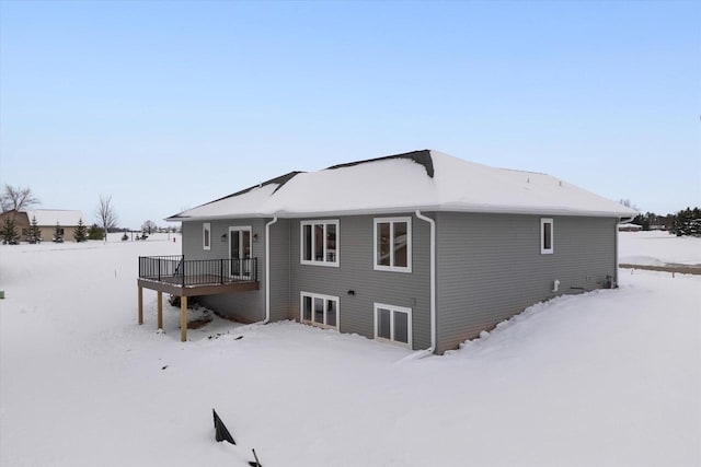 snow covered house featuring a wooden deck