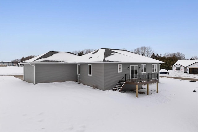 snow covered back of property featuring a deck