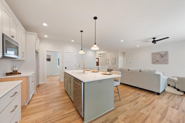 kitchen with sink, pendant lighting, a center island with sink, white cabinets, and appliances with stainless steel finishes