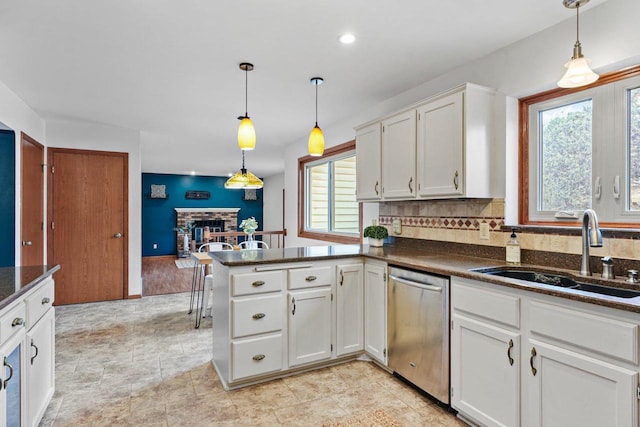 kitchen with dishwasher, sink, white cabinets, and decorative light fixtures