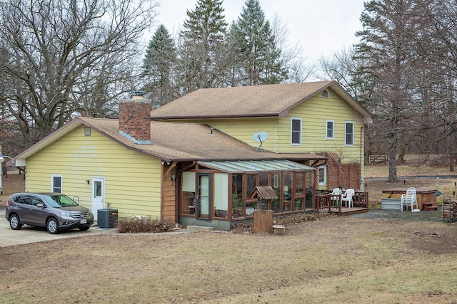 rear view of property featuring central AC, a wooden deck, and a sunroom