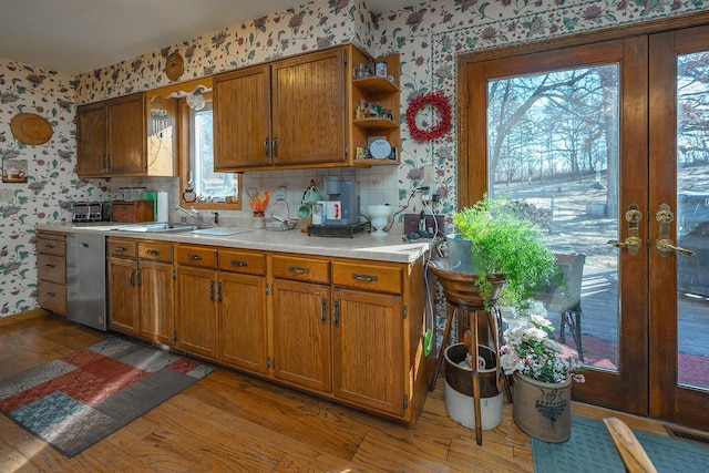 kitchen featuring a wealth of natural light, stainless steel dishwasher, hardwood / wood-style floors, and sink