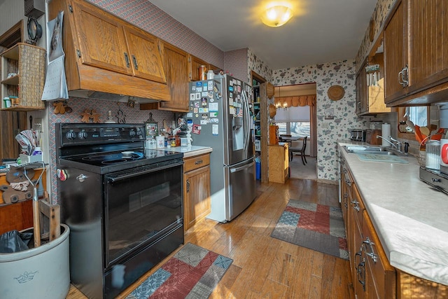 kitchen featuring stainless steel fridge, decorative backsplash, light wood-type flooring, black electric range oven, and sink