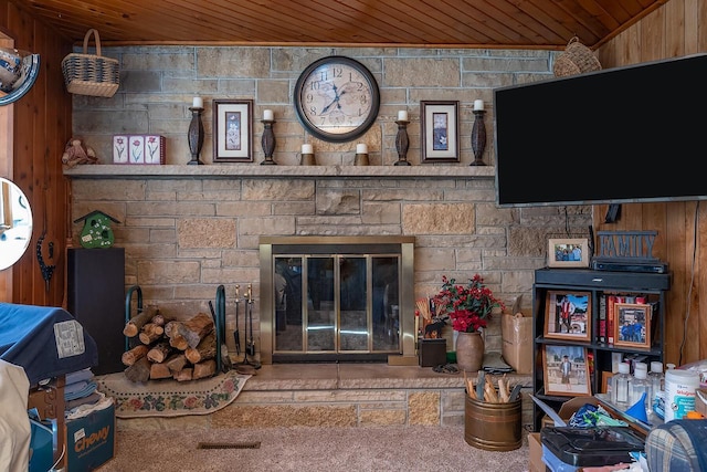 carpeted living room featuring a stone fireplace and wooden ceiling