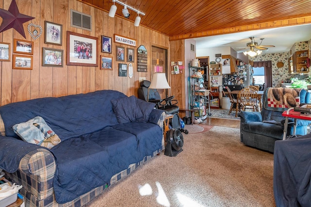 living room featuring ceiling fan, carpet, wooden walls, wood ceiling, and rail lighting