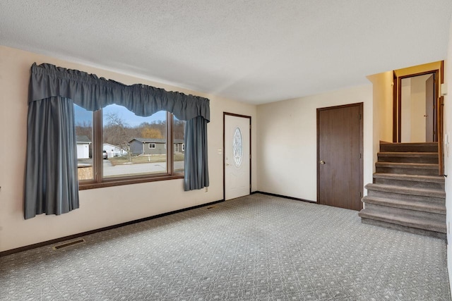 carpeted empty room featuring a textured ceiling