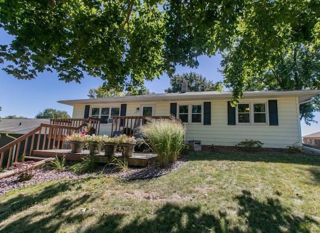 back of property featuring a wooden deck and a yard