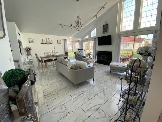 living room with high vaulted ceiling, track lighting, and an inviting chandelier