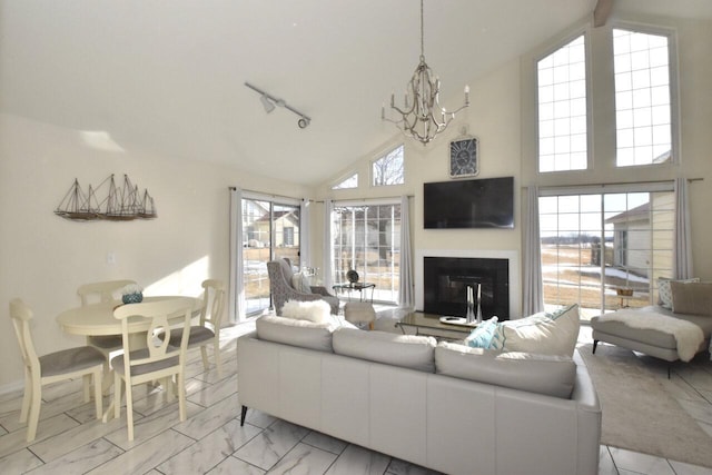 living room with track lighting, high vaulted ceiling, and a notable chandelier