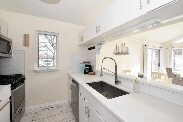 kitchen with white cabinets, appliances with stainless steel finishes, sink, and backsplash