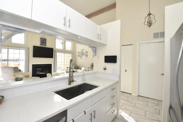 kitchen featuring pendant lighting, white cabinetry, sink, and a high ceiling