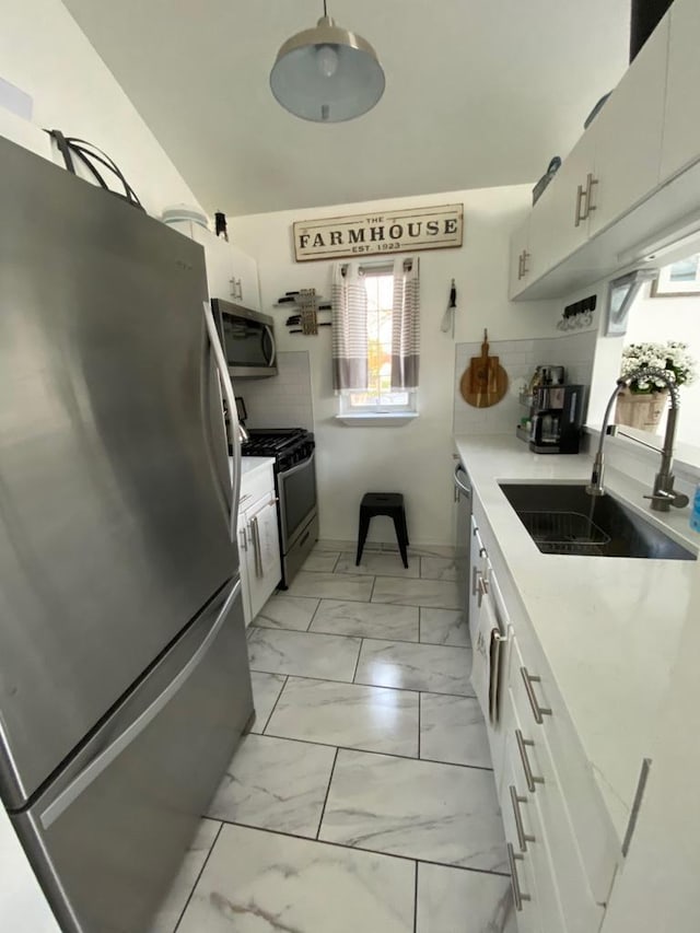 kitchen featuring white cabinetry, appliances with stainless steel finishes, sink, and decorative backsplash