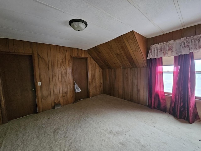 bonus room with carpet flooring, wood walls, a textured ceiling, and vaulted ceiling