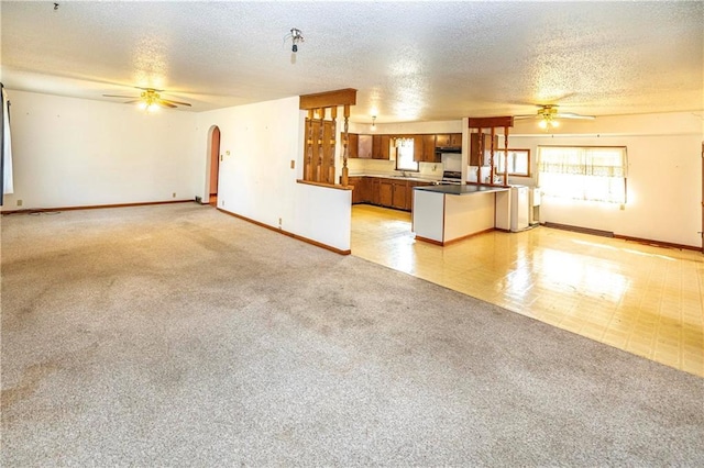 unfurnished living room with ceiling fan, light carpet, and a textured ceiling