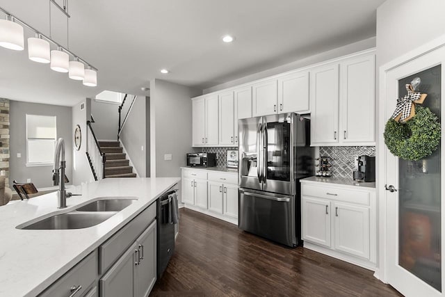 kitchen with white cabinets, sink, tasteful backsplash, decorative light fixtures, and stainless steel appliances