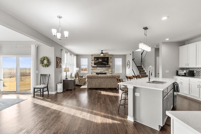 kitchen featuring white cabinets, hanging light fixtures, sink, and a kitchen island with sink