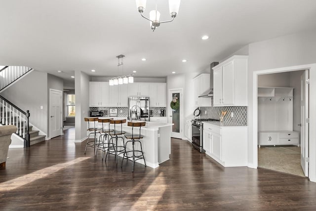 kitchen with dark hardwood / wood-style floors, an island with sink, decorative light fixtures, white cabinets, and appliances with stainless steel finishes