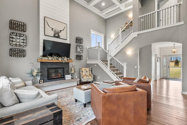 living room featuring a high ceiling, plenty of natural light, coffered ceiling, and beam ceiling