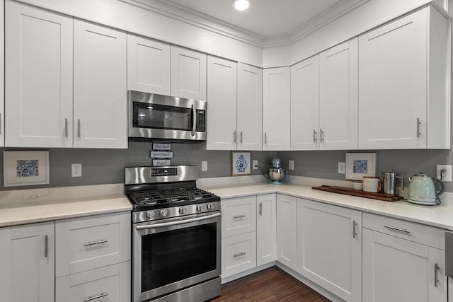 kitchen featuring white cabinets, stainless steel appliances, dark hardwood / wood-style floors, and ornamental molding