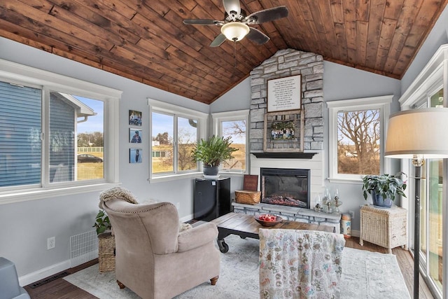 living room with lofted ceiling, a stone fireplace, ceiling fan, light wood-type flooring, and wood ceiling