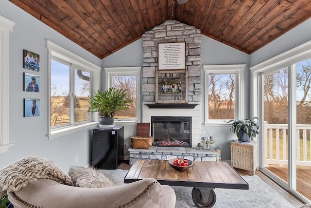 sunroom / solarium with wooden ceiling, vaulted ceiling, and a stone fireplace