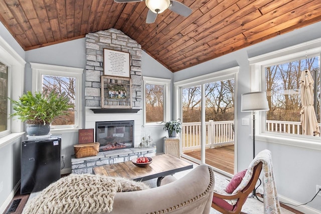 sunroom / solarium featuring ceiling fan, wooden ceiling, a fireplace, and vaulted ceiling