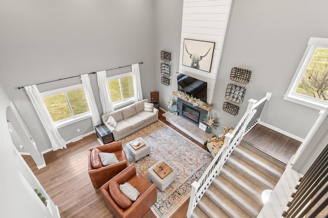 living room featuring a high ceiling, hardwood / wood-style flooring, and a tiled fireplace