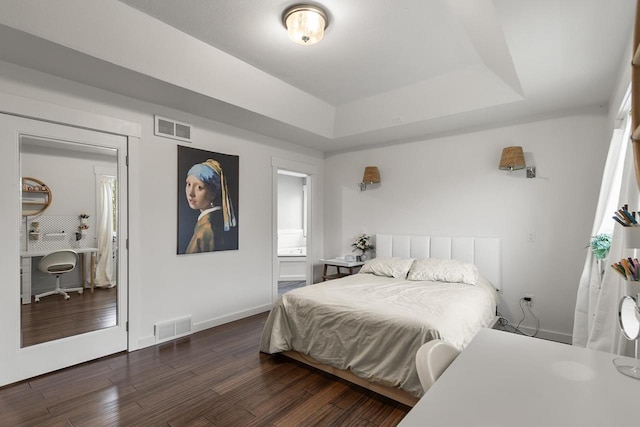 bedroom with a tray ceiling and dark wood-type flooring