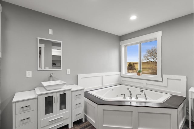 bathroom with hardwood / wood-style floors, vanity, and a tub to relax in