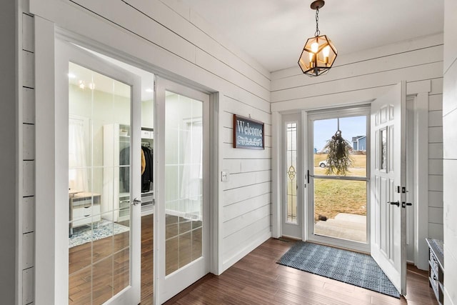 doorway to outside featuring wooden walls and dark wood-type flooring