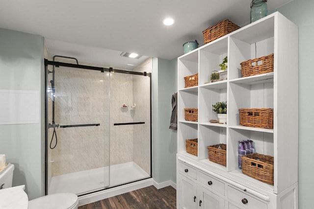 bathroom with hardwood / wood-style flooring, toilet, and a shower with door