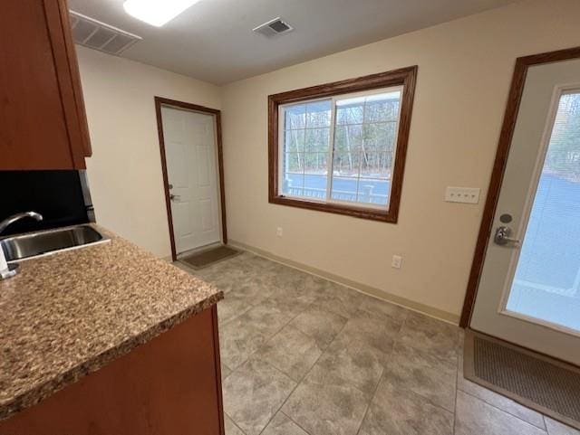 kitchen featuring light stone counters and sink