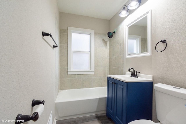 full bathroom with hardwood / wood-style flooring, vanity, toilet, and tiled shower / bath