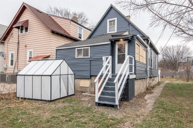 rear view of property with central AC unit and a lawn